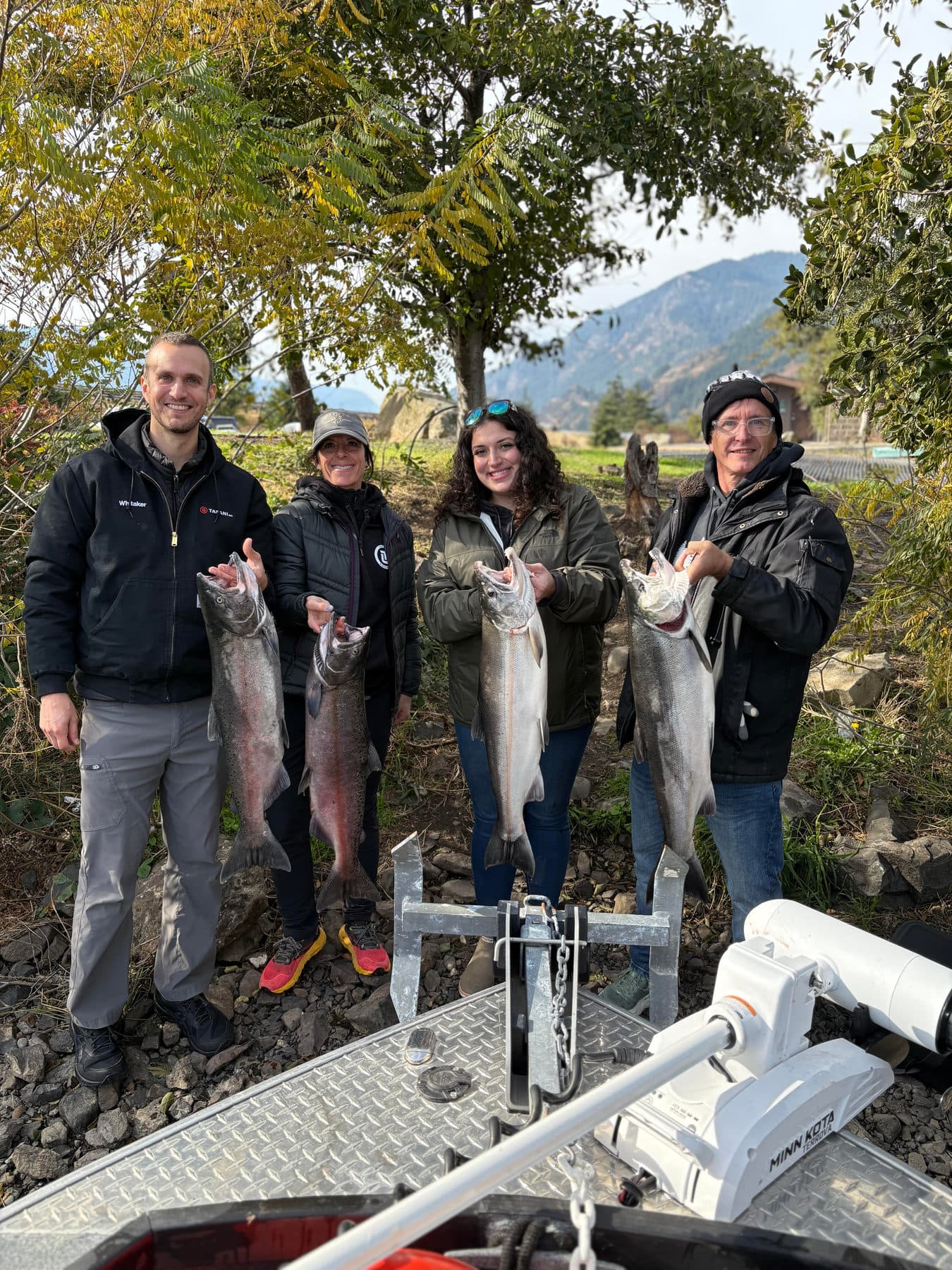 Four anglers holding salmon with the Columbia River Gorge behind them