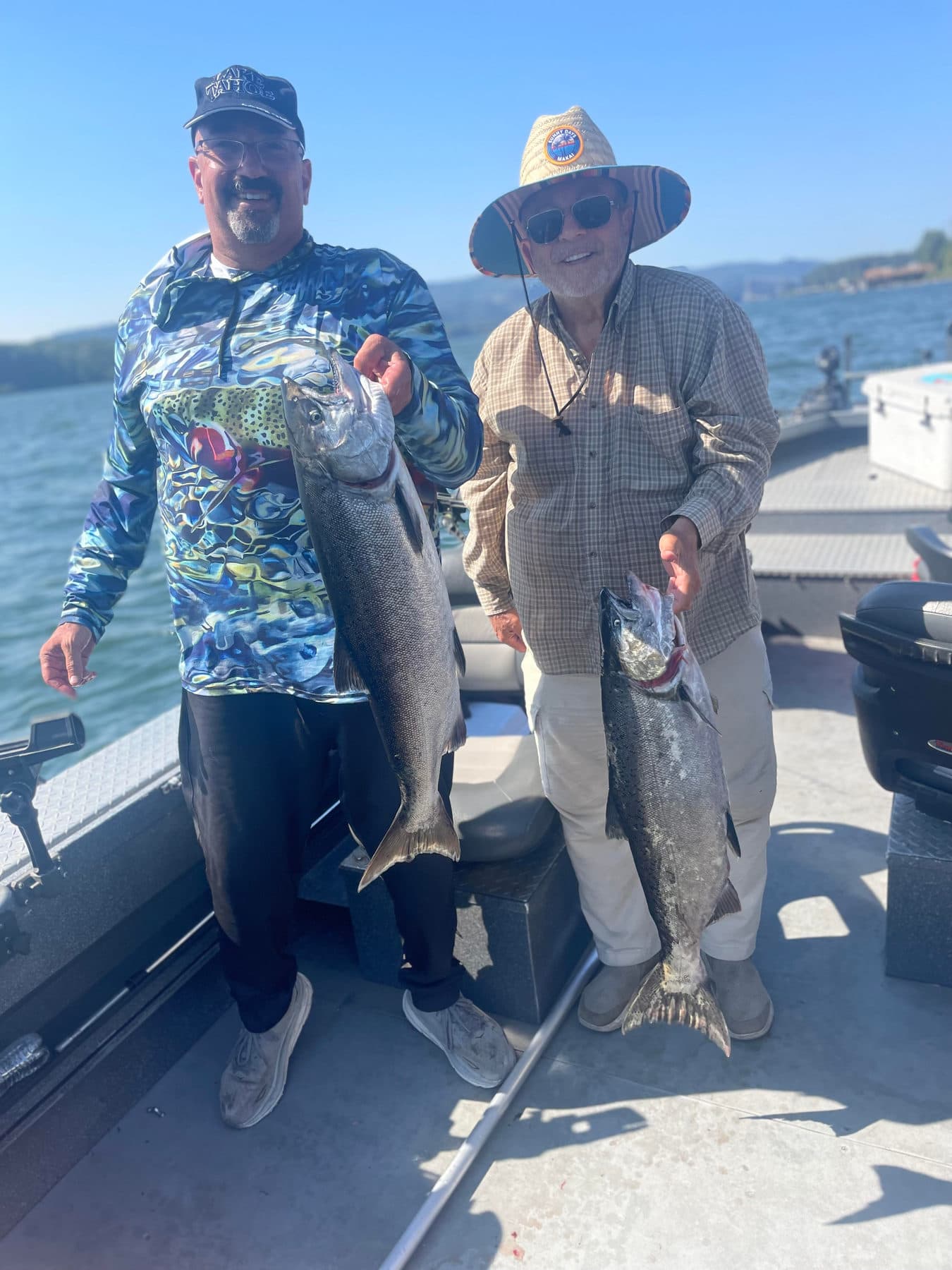 Two anglers holding Spring Chinook salmon on the boat