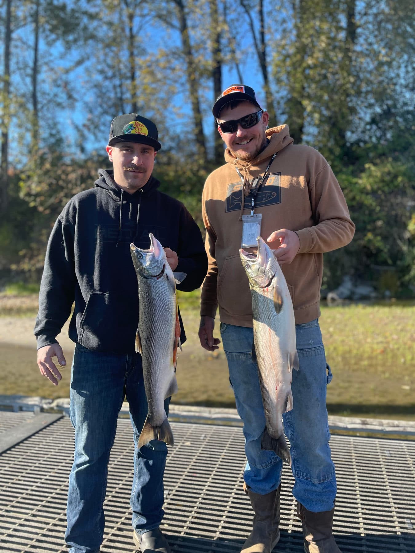Two anglers holding their salmon catch at the dock